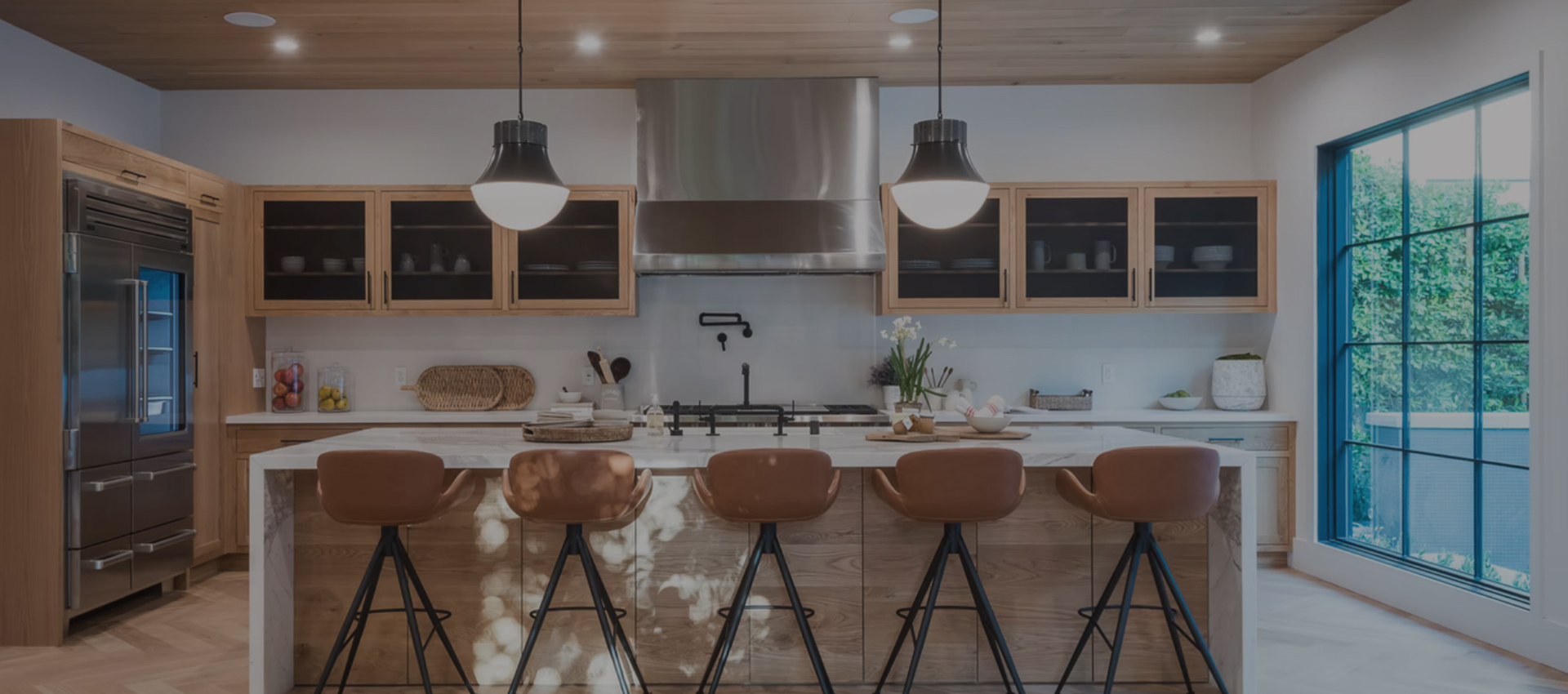 A modern kitchen with stainless steel hood and glass doors.