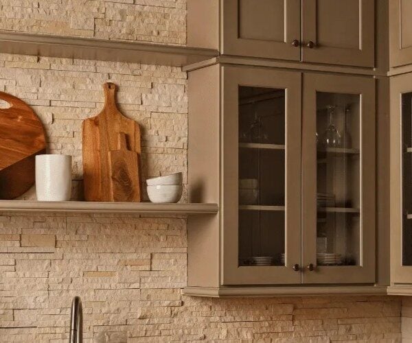 Tan cabinetry with beige dry stacked stone backsplash.
